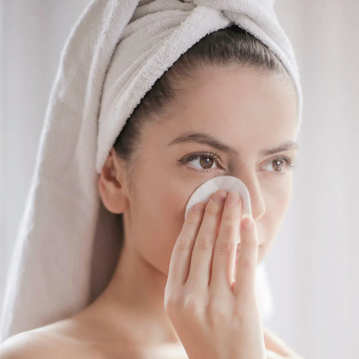 Woman cleansing face with cotton pad