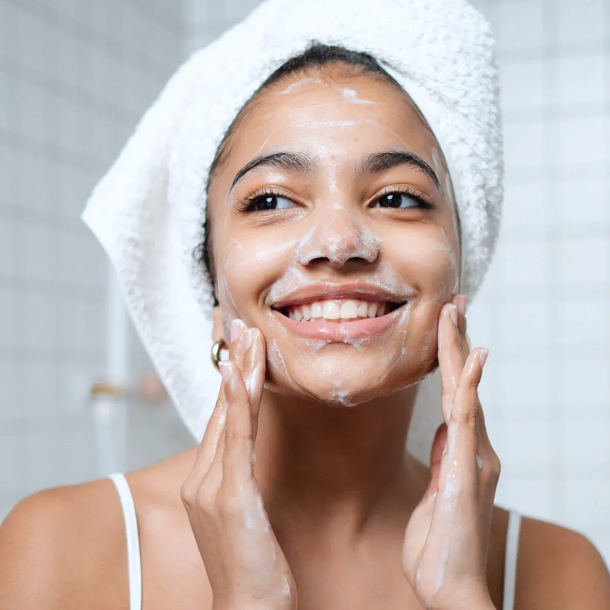 Smiling woman washing face in bathroom